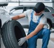 Fresh material. Mechanic holding a tire at the repair garage. Replacement of winter and summer tires