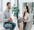 smiling psychiatrist with clipboard talking with happy patient in office