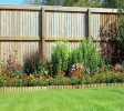 Shrubs And Flowers In A Border With A Grass lawn Surrounded By A